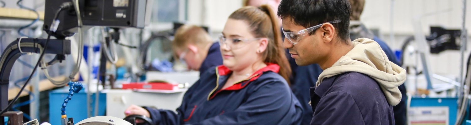 Apprentices at work at engineering workbench 