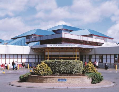 Outside view of Royal Bournemouth Hospital main entrance - blue roof, white two storey building with red sliding doors